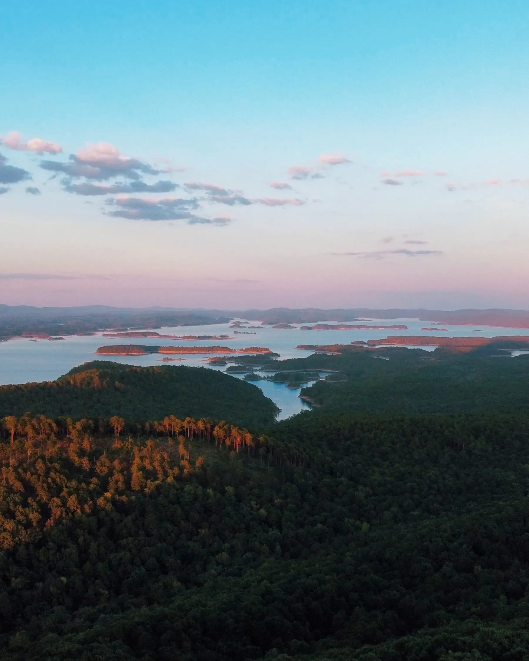Sunset over Lake Ouachita, with pink clouds above forested hills and the lake winding below